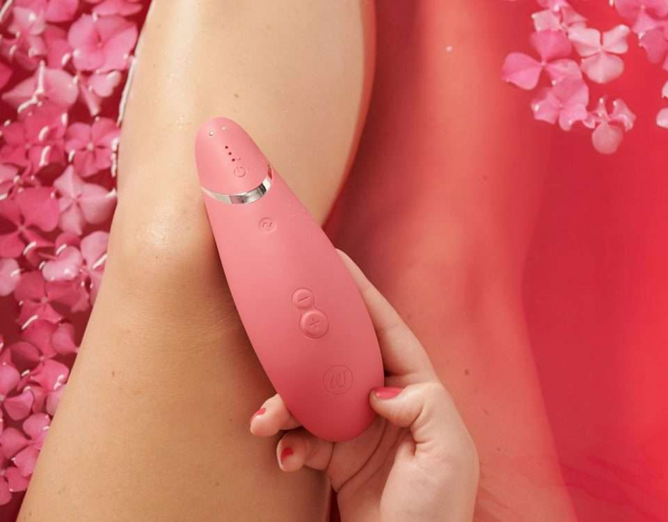 Femeie într-o baie cu petale, ținând în mână un stimulator cu impulsuri de aer, ilustrație pentru ghidul despre cum alegi primul vibrator